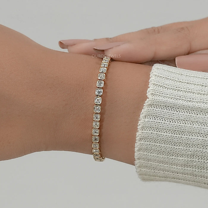 asscher cut lab created diamonds bezel set tennis bracelet in yellow gold on hand