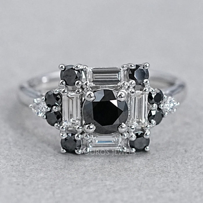 top view of black round diamond baguette halo engagement ring on grey fabric