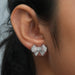 Bow Shaped Round Stud Diamond Earrings elegantly worn on an ear, showcasing intricate white and pink diamond detailing.