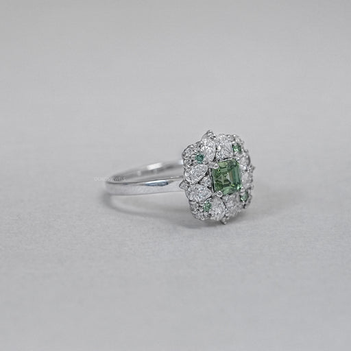 asscher cut green diamond cluster engagement ring's side view on grey fabric