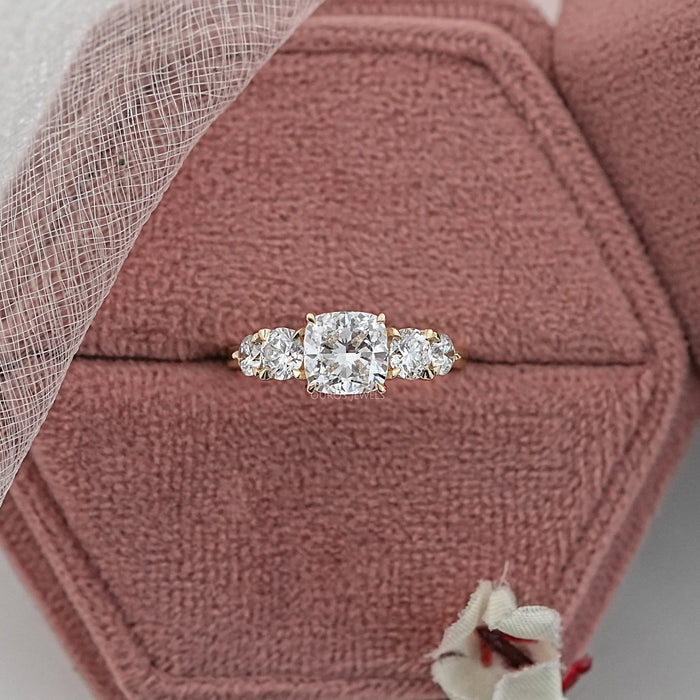 cushion cut diamond five stone engagement ring in yellow gold band in jewelry box