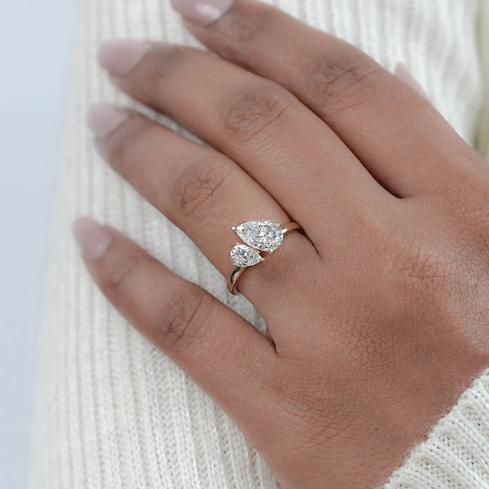 two pear-cut diamond toi et moi engagement ring on model's finger with yellow gold band