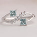 front view of green princess-cut lab diamond dainty wedding ring on grey fabric