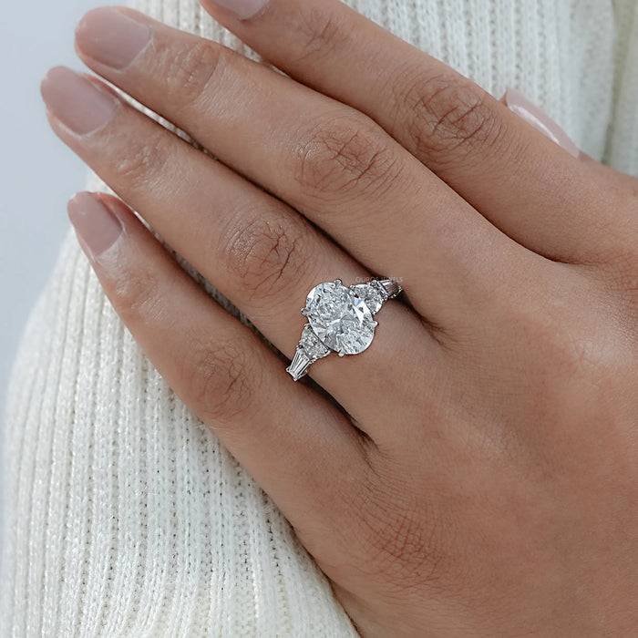 oval and half moon cut diamond five stone engagement ring on model's finger