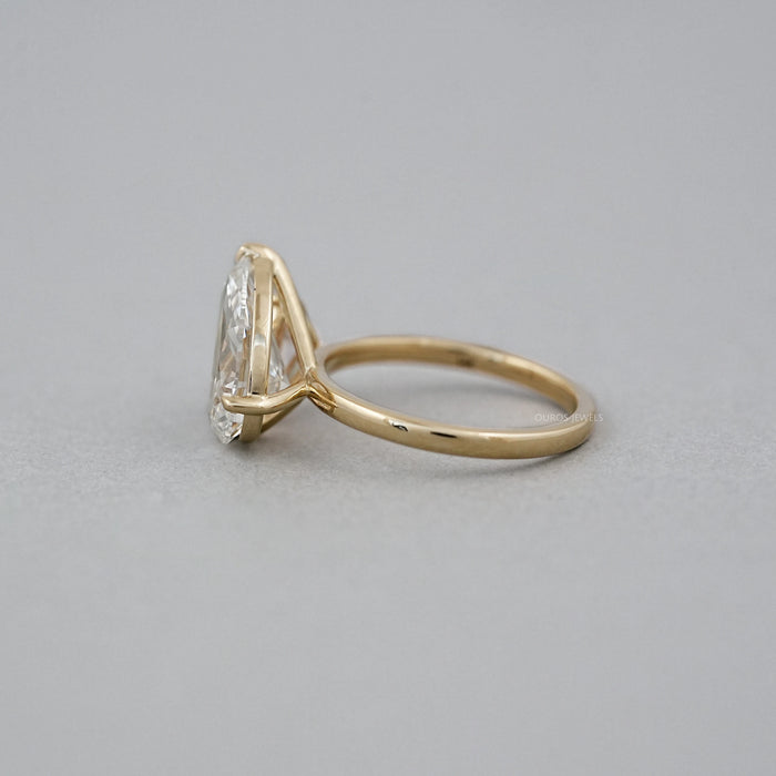 side view of pear lab diamond dual toi et moi engagement ring on grey fabric