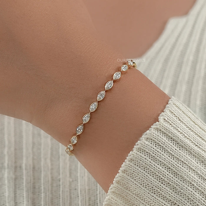 east west set maquise cut man made diamonds bezel set tennis bracelet in yellow gold on hand