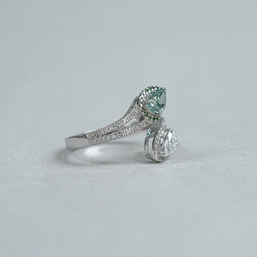 side view of fancy vivid green pear cut diamond bypass halo ring on grey fabric
