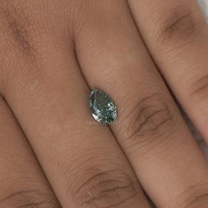 1.62 Carat Fancy Vivid Green Pear Cut Lab Grown Diamond placed on a person's finger for scale, showing the diamond's size and color against the skin.