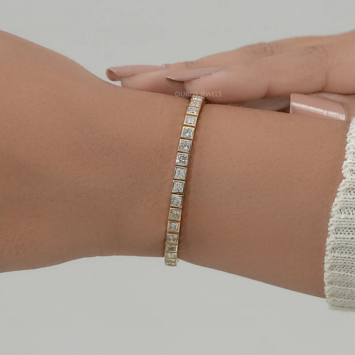 princess cut lab produced diamonds bezel set tennis bracelet in yellow gold on hand