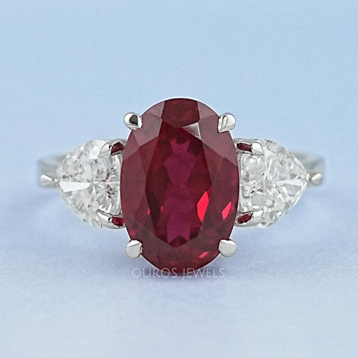 front view of oval ruby gemstone with heart diamond 3 stone engagement ring