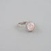 side view of pink round-cut diamond solitaire halo engagement ring on grey fabric