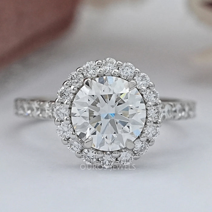 front view of round cut lab diamond halo engagement ring on grey fabric