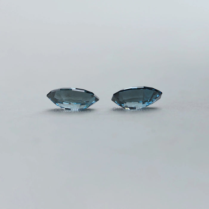 side view of step cut blue oval shaped lab created diamonds pair