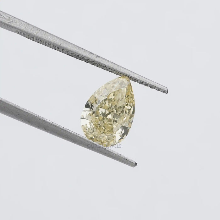 2.17 Carat Fancy Yellow Pear Cut Loose Diamond held by tweezers against a white background, showcasing its sparkling clarity and yellow color.