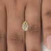 2.17 Carat Fancy Yellow Pear Cut Loose Diamond placed on a person's finger, highlighting its size, brilliance, and vibrant yellow color against the skin.