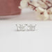 Butterfly Cut Diamond Stud Earrings featuring two sparkling diamonds set against a soft, blurred floral background.