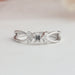 Close up view of man made emerald cut cluster diamond ring set in side small round cut diamonds.
