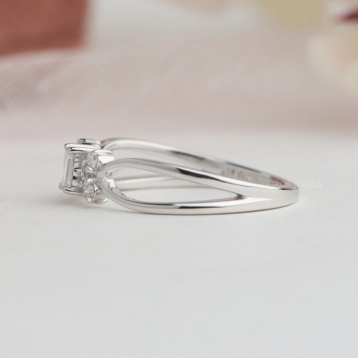 Side view of emerald cut cluster diamond ring with round cut side diamonds.