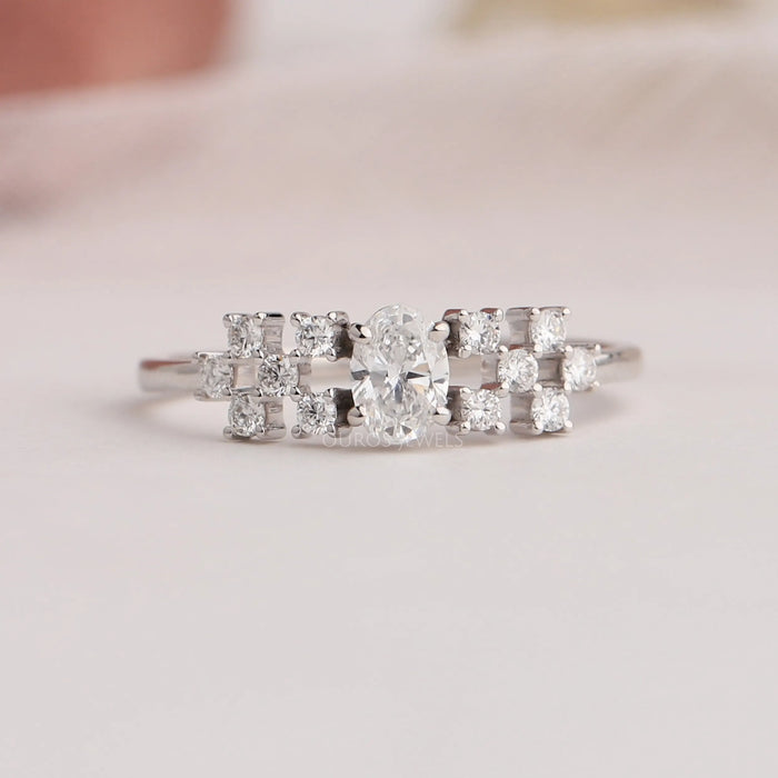 Close up view of oval cut cluster diamond ring with side round cut small diamonds.