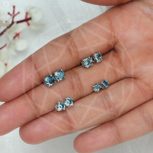 Blue Cushion Diamond Stud Earrings in various sizes, beautifully arranged on a hand